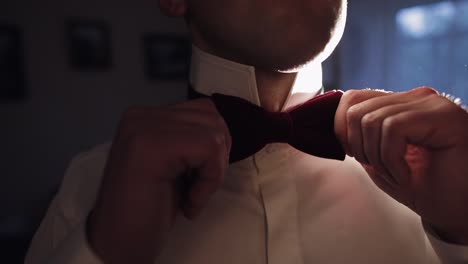 Groom-adjusts-bow-tie,-preparing-to-go-to-the-bride,-businessman-in-white-shirt,-wedding-day