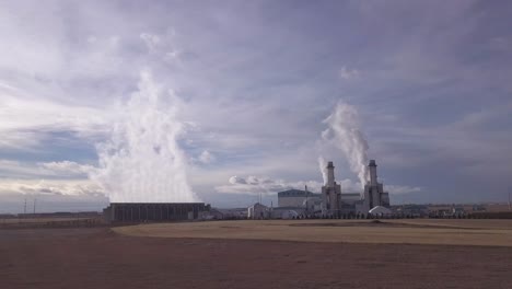 pan right on steam powered electrical turbines with dramatic blue sky