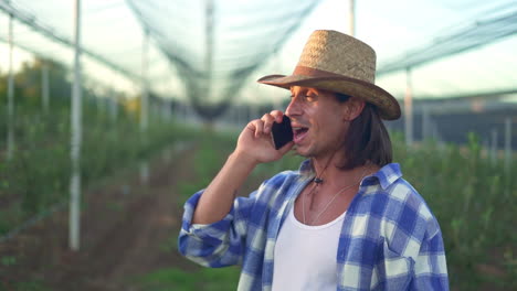 farmer talking on mobile phone in an orchard