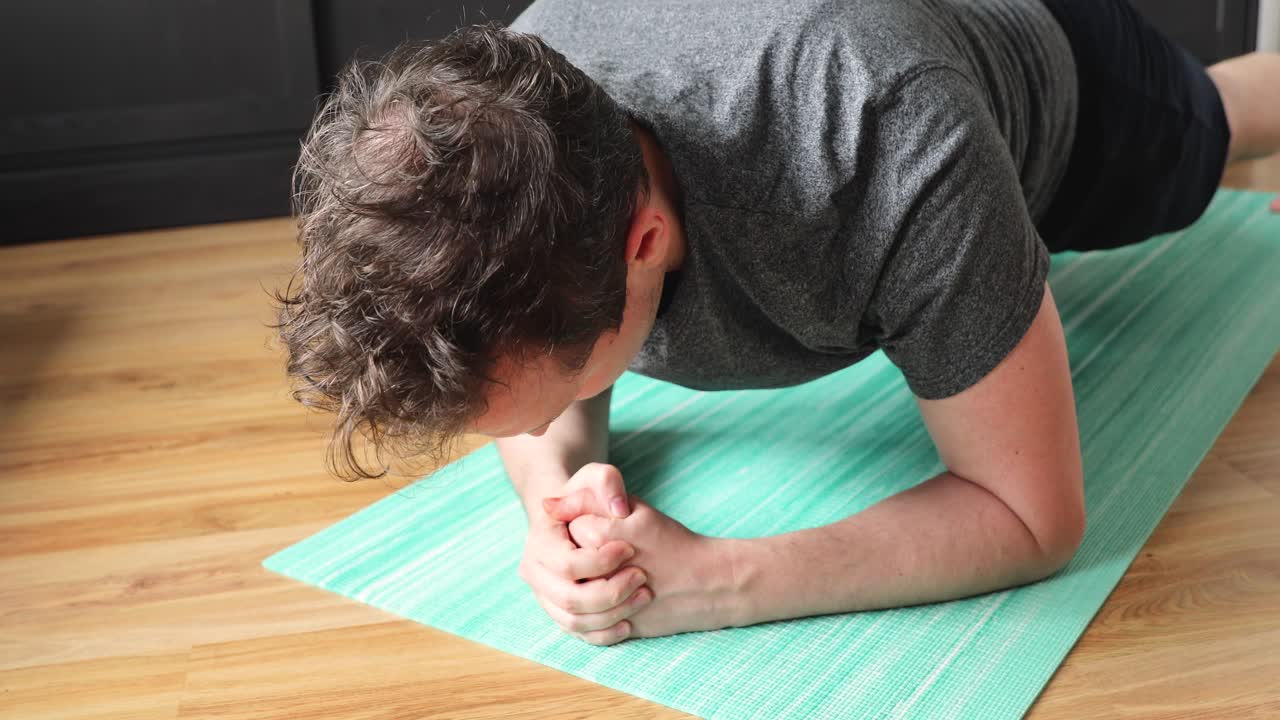 young man doing his workout at home in the living room - plank exercise