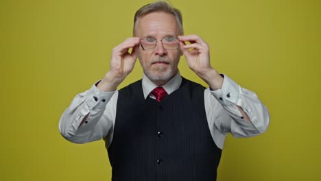 funny grey-haired man with glasses. portrait of a mature man in suit putting on glasses with a funny view. slow motion. positive emotions.