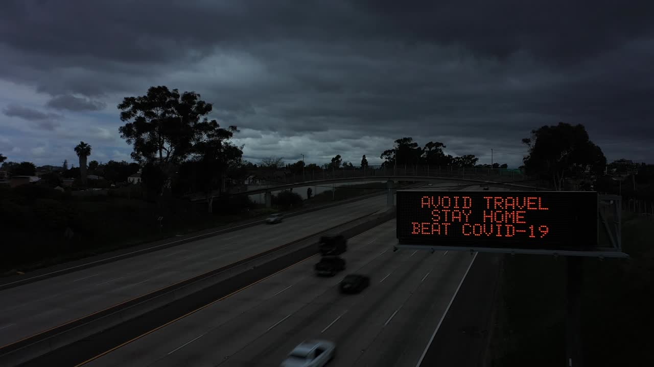 어두워진 고속도로를 따라 있는 공중 표지판은 사람들에게 covid19 코로나바이러스 전염병 발발 1 동안 여행을 피하라고 말합니다.