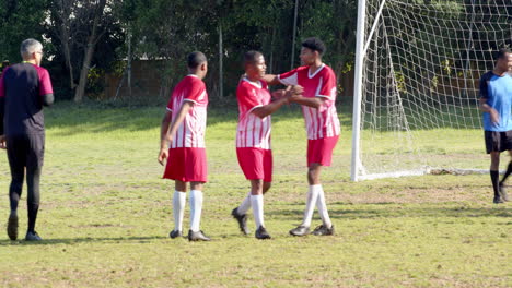 celebrating after scoring goal, soccer players in red uniforms on field