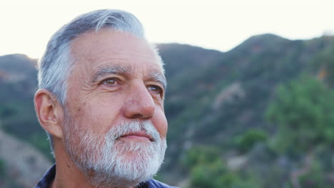 portrait of smiling hispanic senior man outdoors in countryside