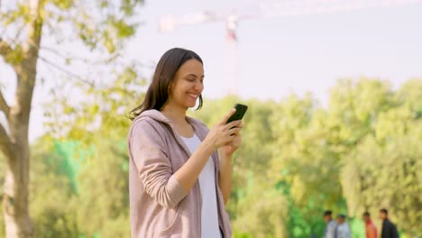 girl using phone while walking in a park in morning time