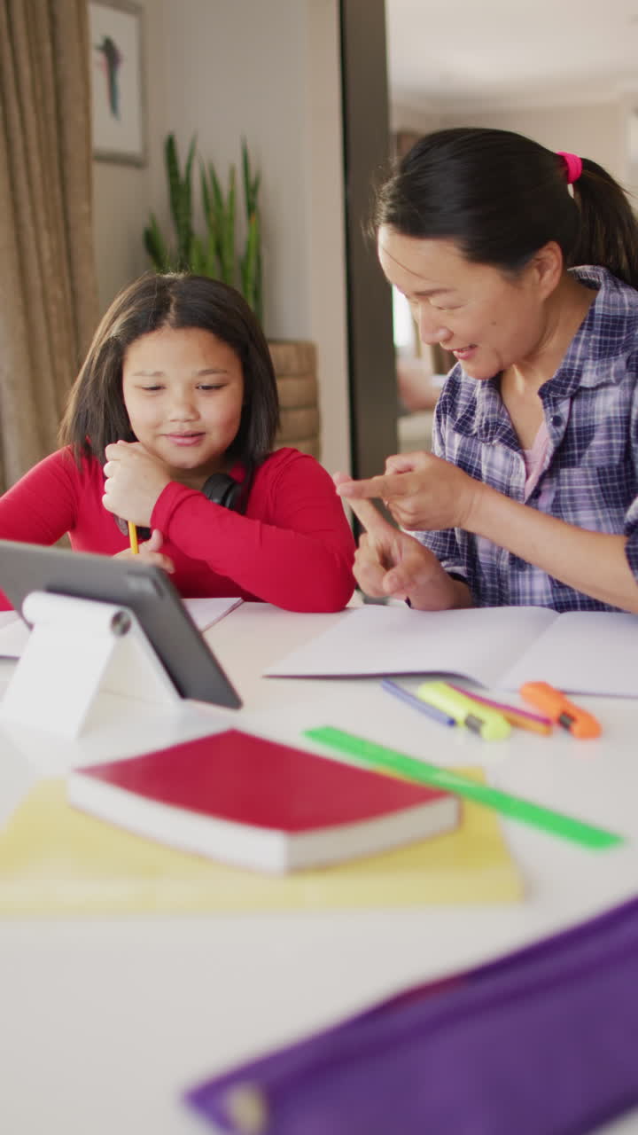 video vertical de una madre y una hija bi-raciales felices usando una tableta en casa