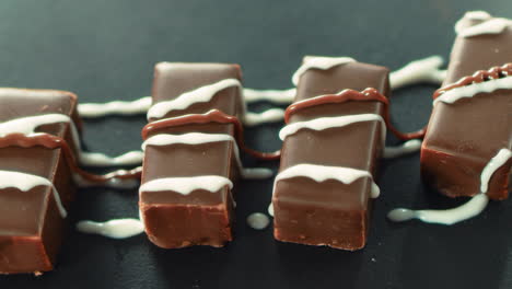 Closeup-hot-caramel-pouring-on-chocolate-candies-in-slow-motion