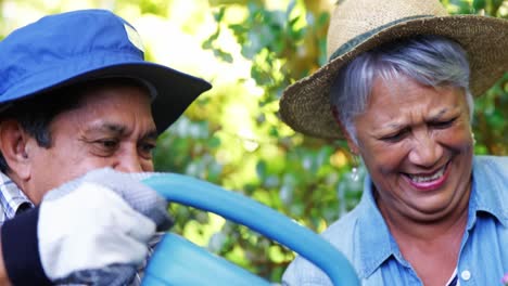 Senior-couple-watering-plants-with-watering-can-in-garden-