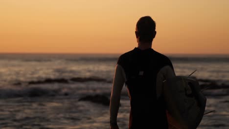 Man-standing-with-surfboard-in-the-beach-4k