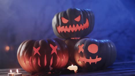 Video-of-halloween-carved-pumpkins-and-smoke-with-copy-space-on-blue-background