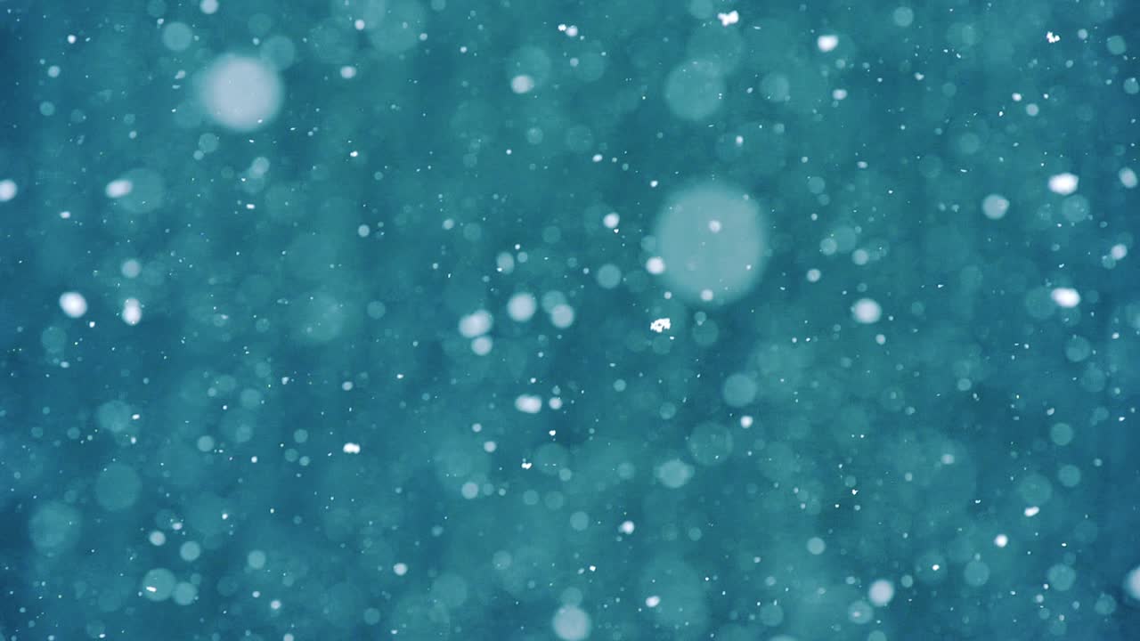 Peaceful winter scene with snowflakes falling slowly on blue blurred background