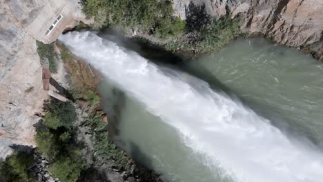 jet of water emerges from arenoso reservoir spillway, el chorro, spain, aerial top down