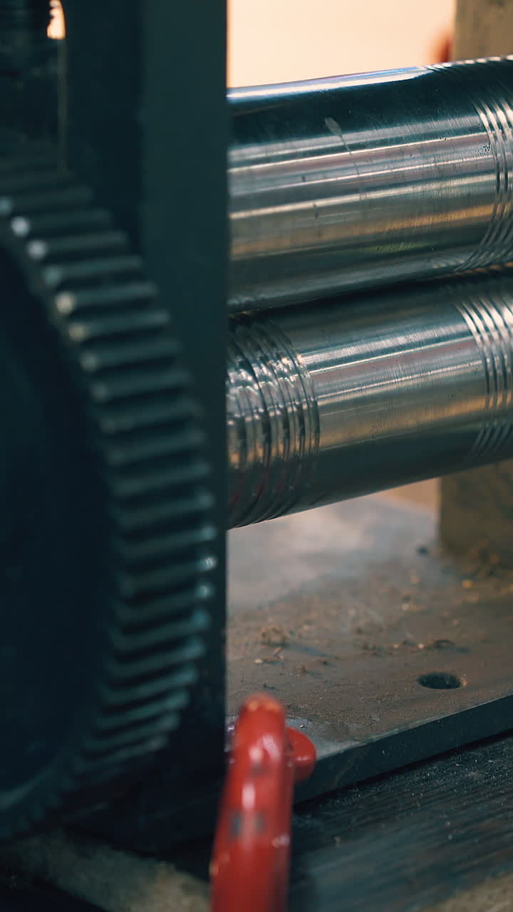 CU: skilled goldsmith forge-rolls piece of metal with machine tool form at workplace in light workshop close view