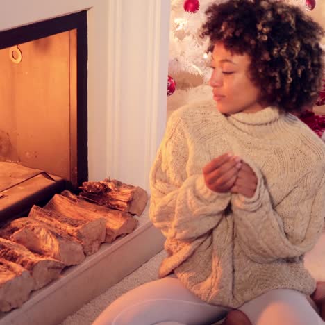 woman seated by fireplace and holiday setting