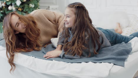 smiling ladies starting pillow fight on bed in luxury apartment.