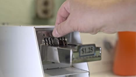 close up from hand is adding coins to dryer machine