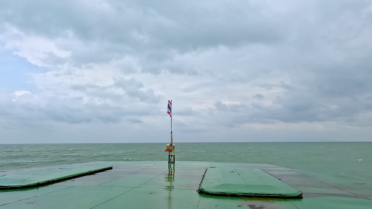 A tranquil ferry journey across calm waters in Koh Samui, Thailand, with a prominently displayed Thai flag and overcast skies