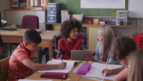 Profesora-Enseñando-A-Un-Niño-Discapacitado-Mediante-El-Uso-De-Una-Tableta-Digital-En-La-Escuela