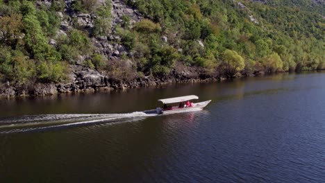 Drone-following-boat-with-tourists-at-Lake-skadar-Montenegro-during-day-time,-aerial