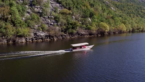 drone following boat with tourists at lake skadar montenegro during day time, aerial