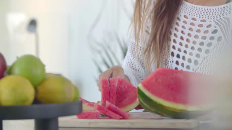 female hands use a large knife to cut a ripe red watermelon into even pieces