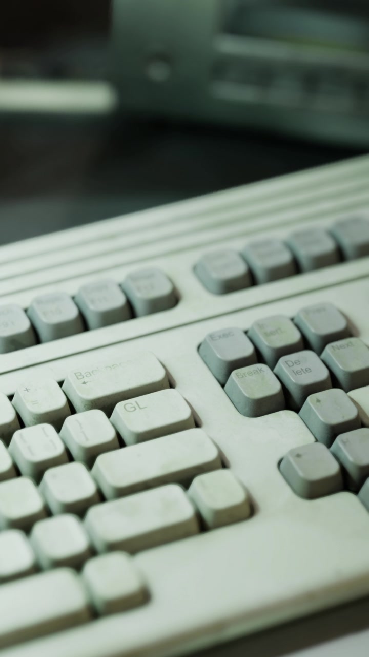 Gammelt tastatur på et skrivebord med slidte taster og tydelige tegn på brug.
