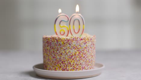 studio shot birthday cake covered with decorations and candle celebrating sixtieth birthday being blown out