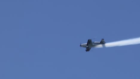 avión único ejecutando maniobras aéreas con rastro de humo