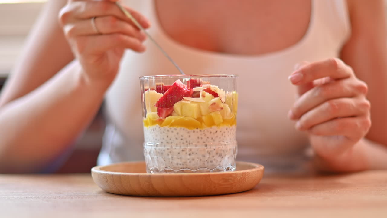 Donna che mangia un pudding di chia con frutta su un tavolo in un ristorante