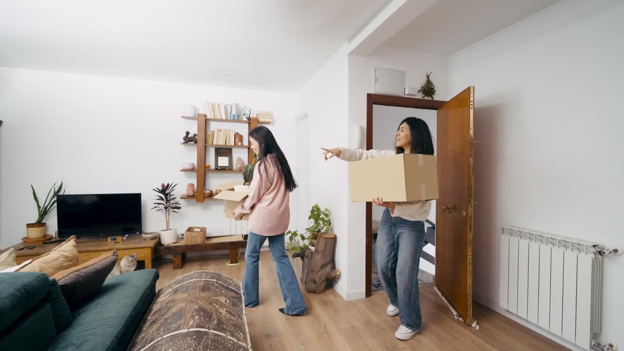 Jovens Mulheres Felizes Carregando Caixas para um Novo Apartamento.