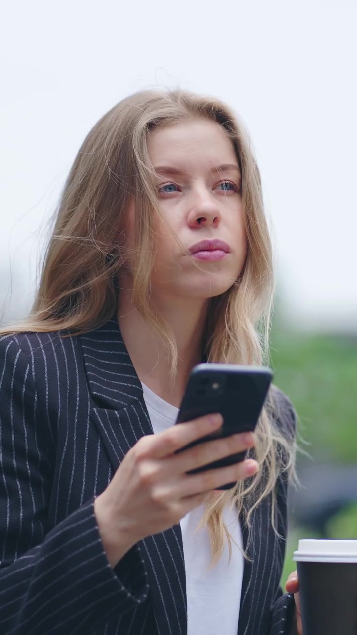 Giovane imprenditrice che usa lo smartphone e beve caffè all'aperto