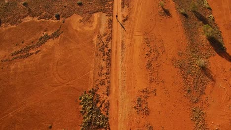 a person walks alone down down a remote, red earth australian outback road