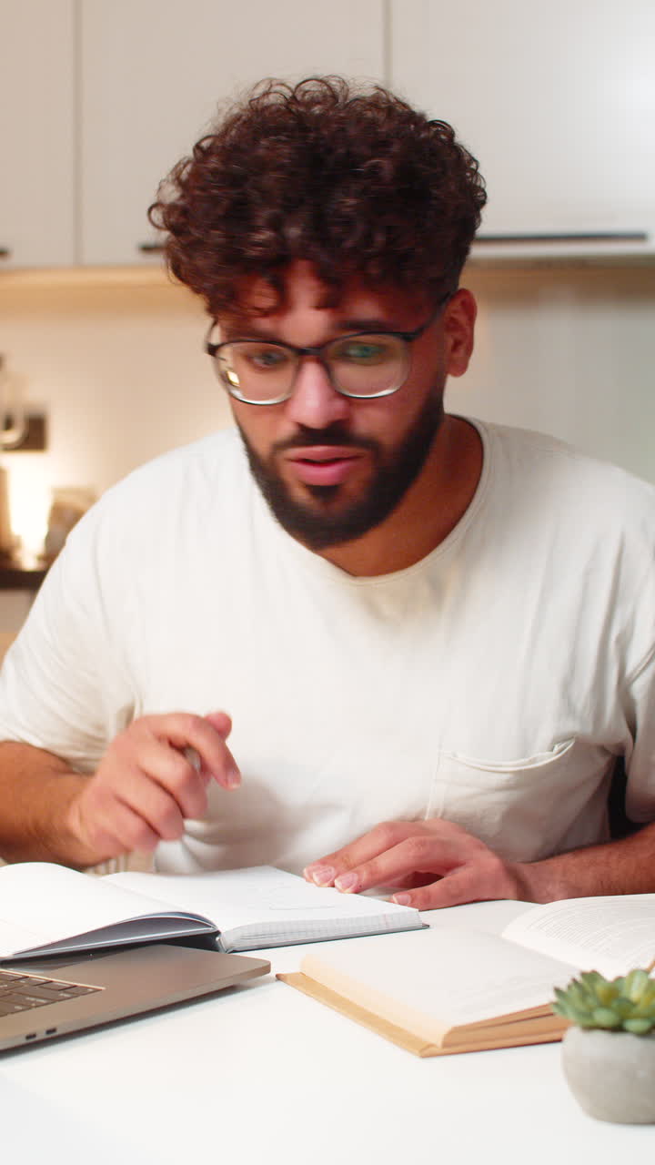 Arabian man studies online on laptop writes notes from video course prepares for exam at night