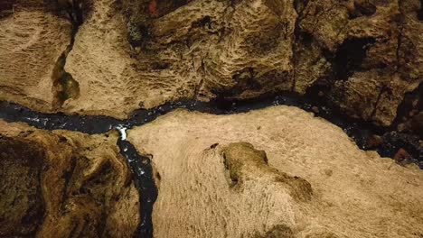 aerial view over a stream of water flowing in a gorge in iceland, during winter time