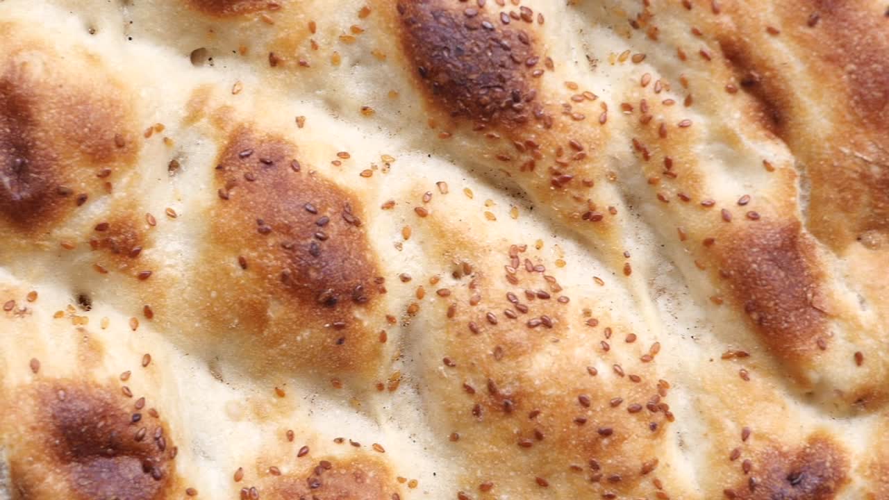 Nærbilde av roterende tradisjonelt pide-brød med sesamfrø.