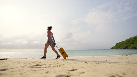 mujer asiática de 4k arrastrando una maleta y caminando por una playa tropical al atardecer de verano.
