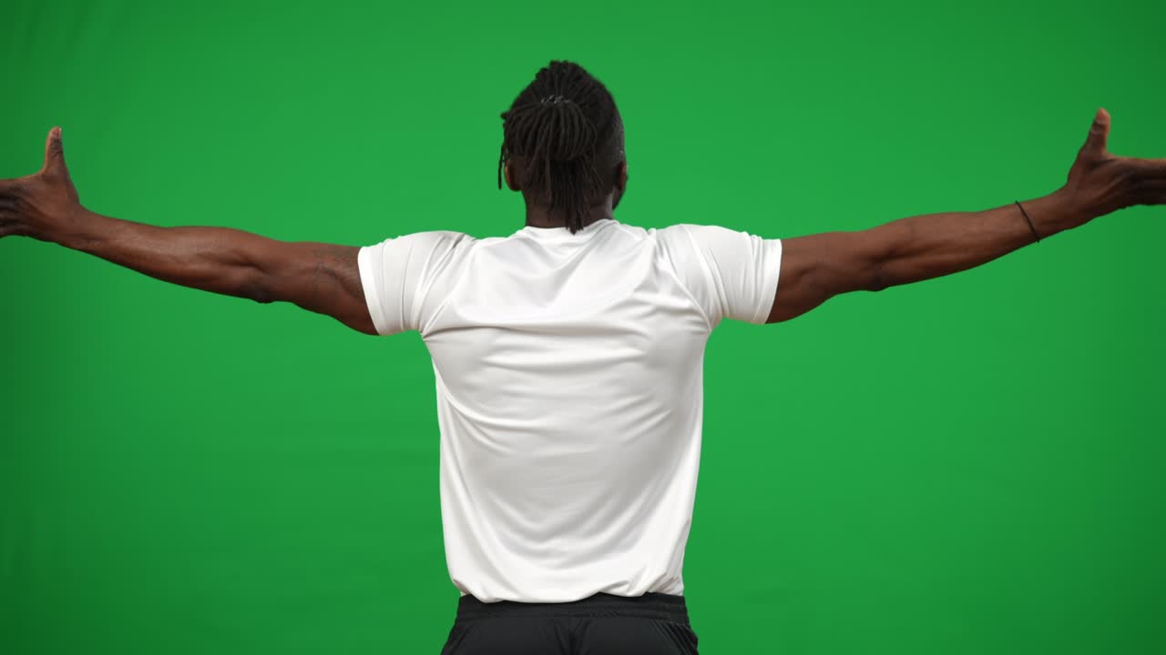 vista de atrás satisfecho futbolista afroamericano estirando las manos en el fondo de chromakey animando. feliz deportista saludando a los fanáticos en la pantalla verde. emoción y concepto de éxito.