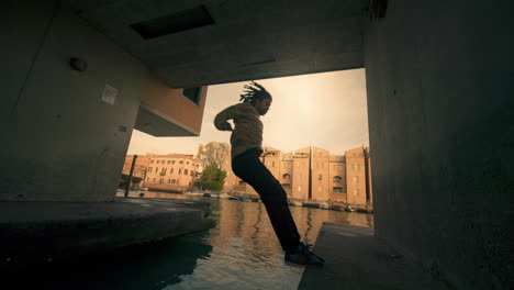 man jumping over canal in urban setting