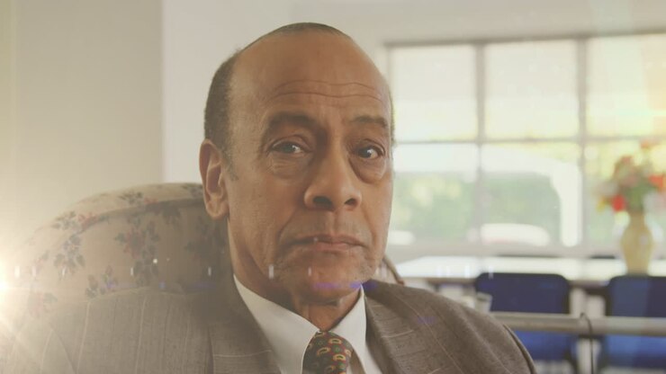 Animation of glowing light over serious senior man at home