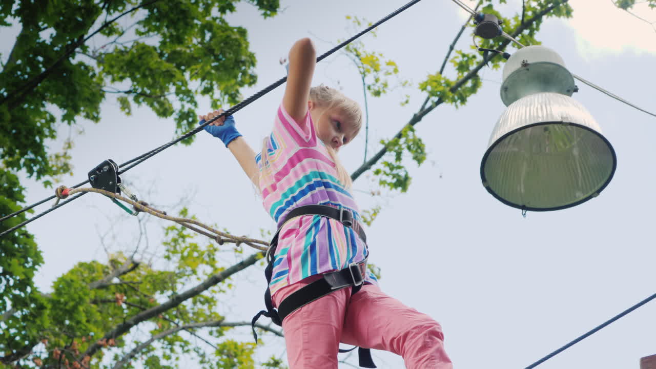 una chica valiente se mueve a lo largo de las cuerdas entre los árboles usa una cuerda de seguridad