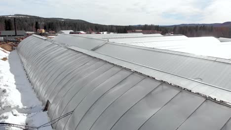 Greenhouses-Large-complex-in-plant-nursery-amidst-snow-capped-Sweden---Aerial-low-orbit-shot