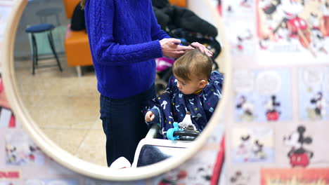 mother giving baby a haircut at a salon