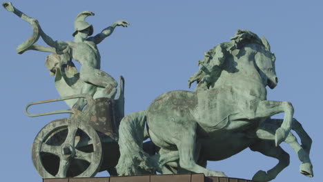 vista lateral de la antigua estatua de un hombre en un carro como símbolo de guerra y victoria