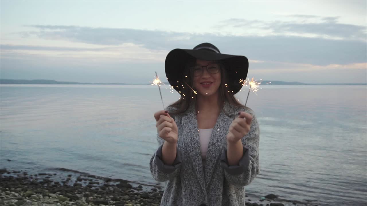 mujer con chispas en una playa junto al lago
