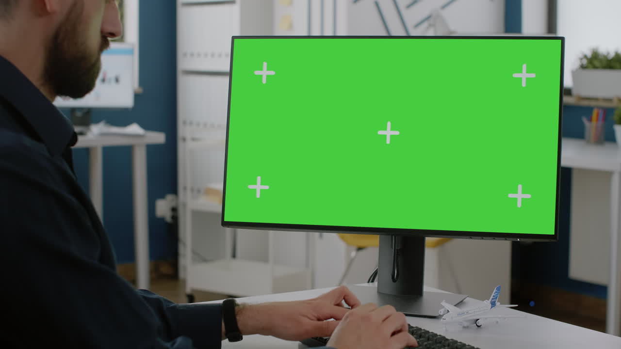 Close up of man typing on keyboard with green screen on monitor