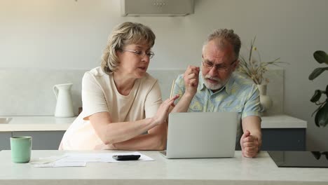 retired couple check bank account using laptop annoyed with overspending