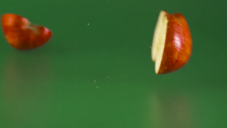 manzana roja cayendo y rompiéndose por la mitad sobre un fondo verde
