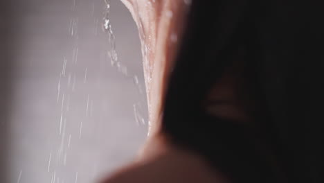 woman neck with water drops in shower unit closeup. graceful lady relaxes standing in warm sprays in home bathroom. hygienic routine for body