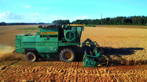 side view of mechanical grain reaping machine cutting mature crops on farmland