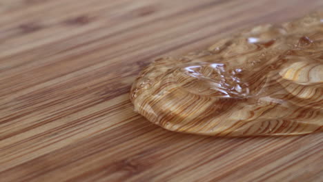 líquido de gel desinfectante para manos derramado y deslizándose sobre una superficie de madera